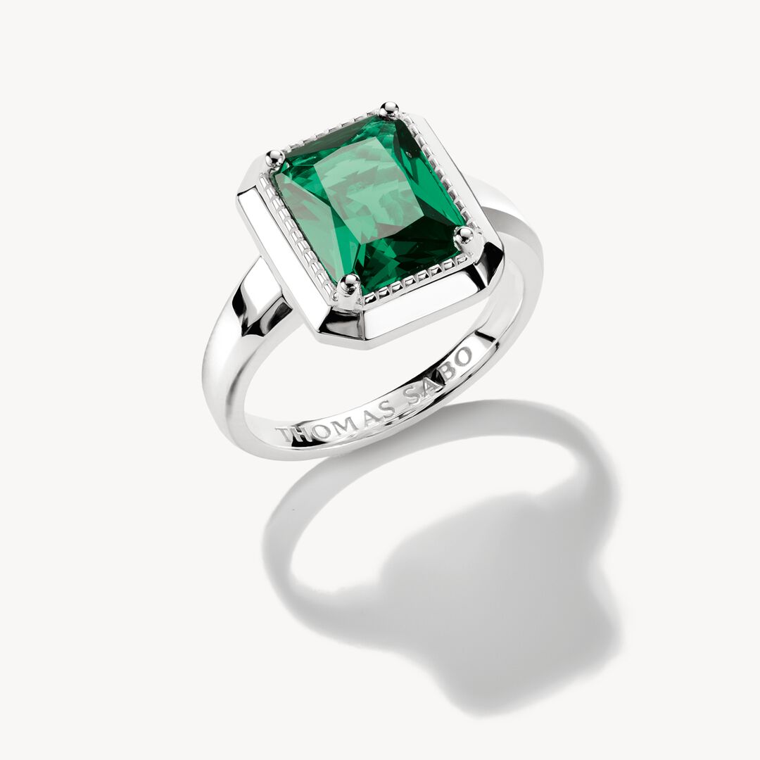 Silver ring with a green gemstone on a white background