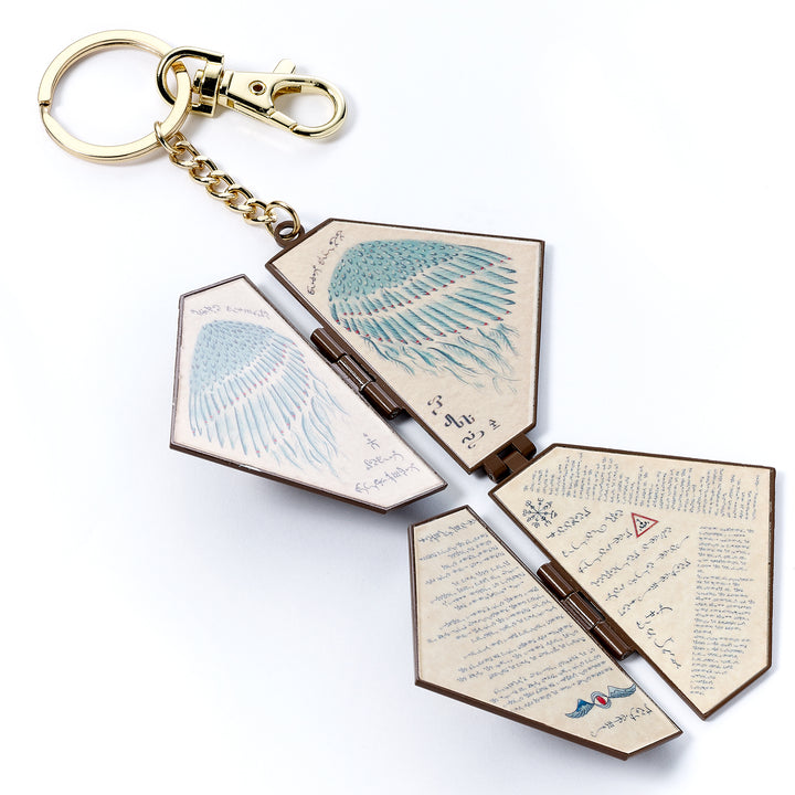 Keychain with open book design featuring text and illustrations on a white background