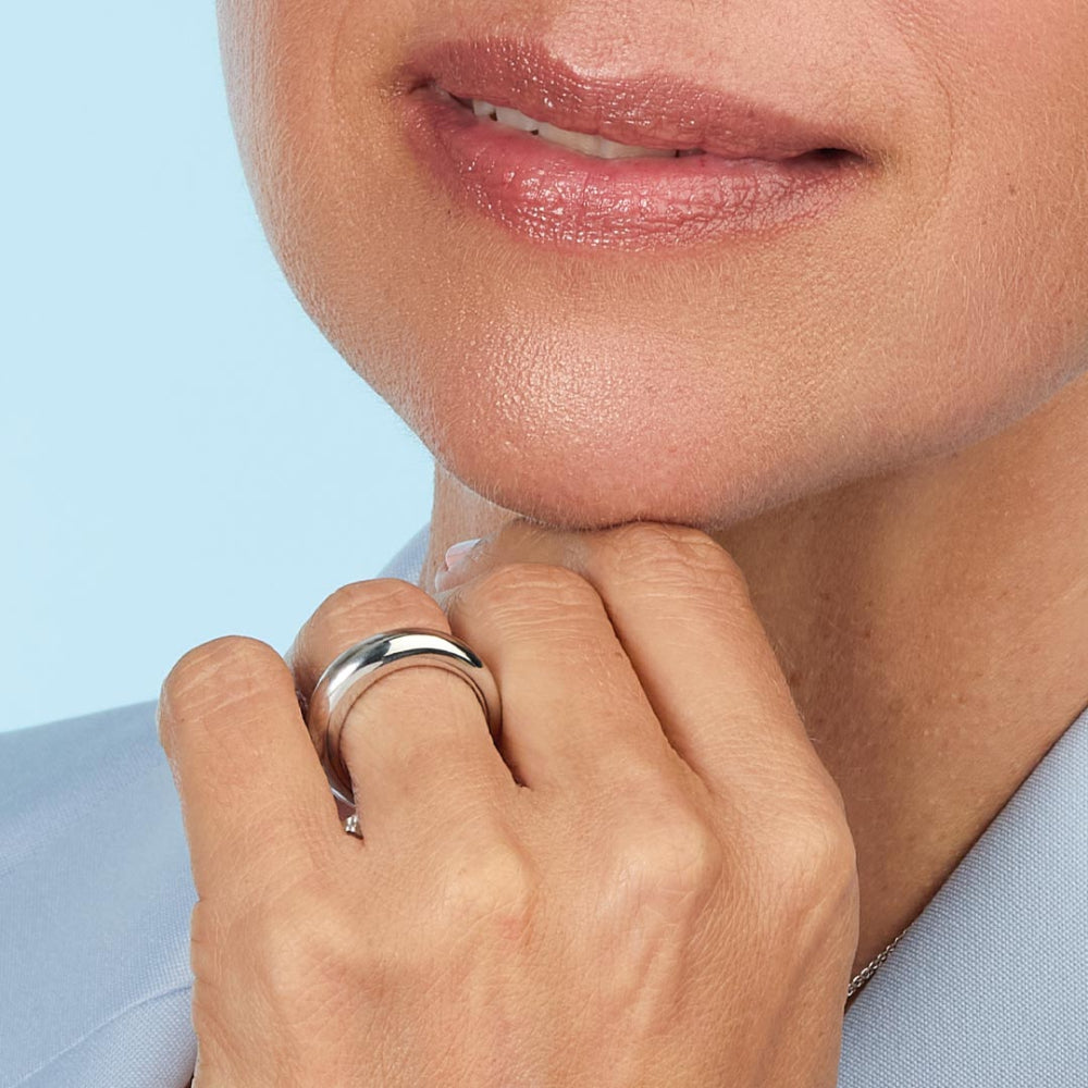 Close-up of a person's hand with a ring on a light blue background