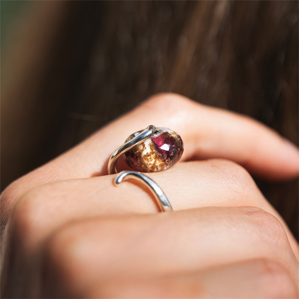 Close-up of a hand wearing two rings with gemstones on a blurred background