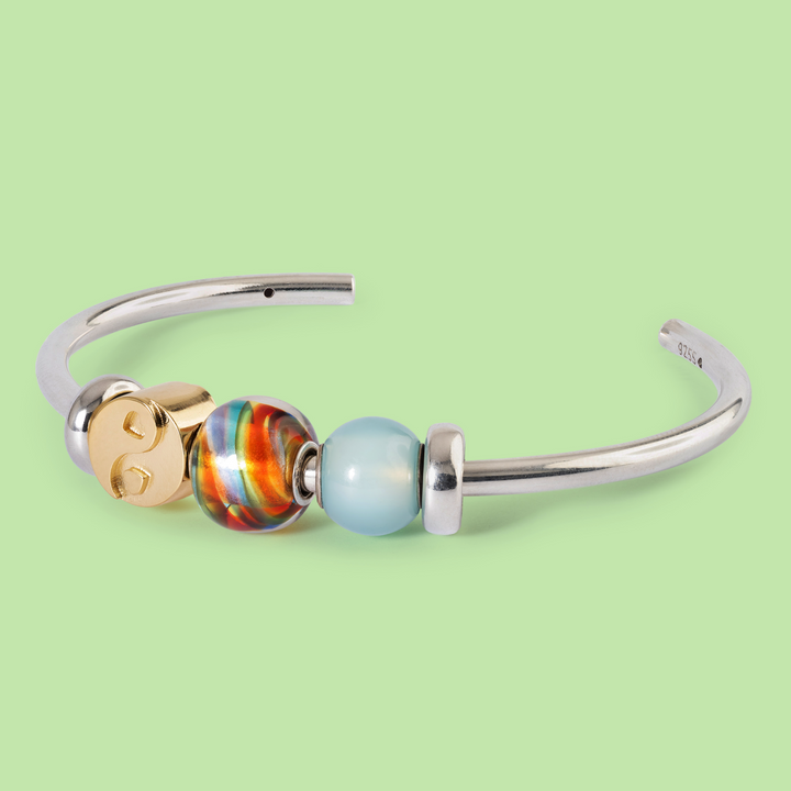 Silver bracelet with colorful beads on a light green background