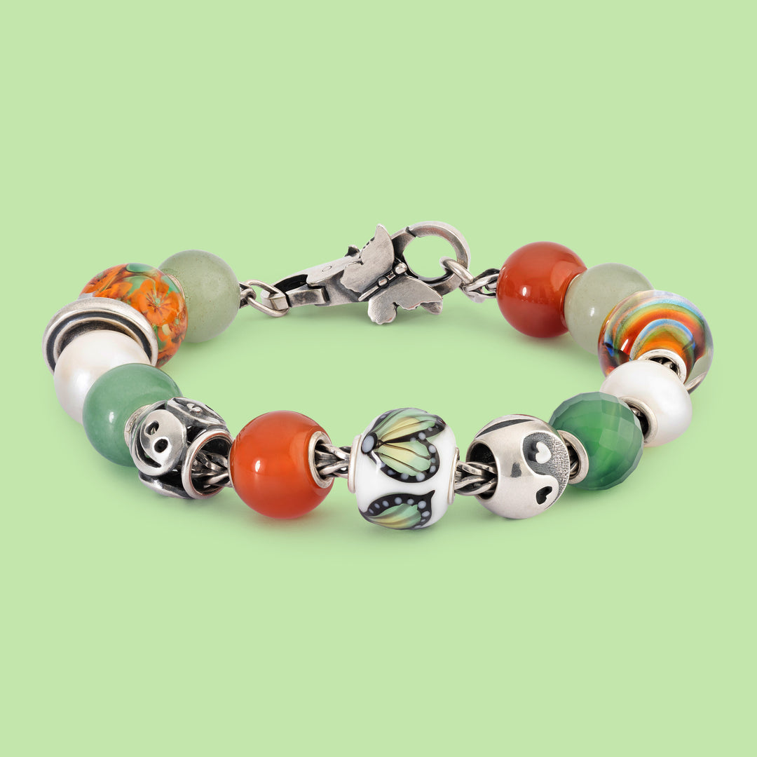 Bracelet with colorful beads and silver charms on a light green background