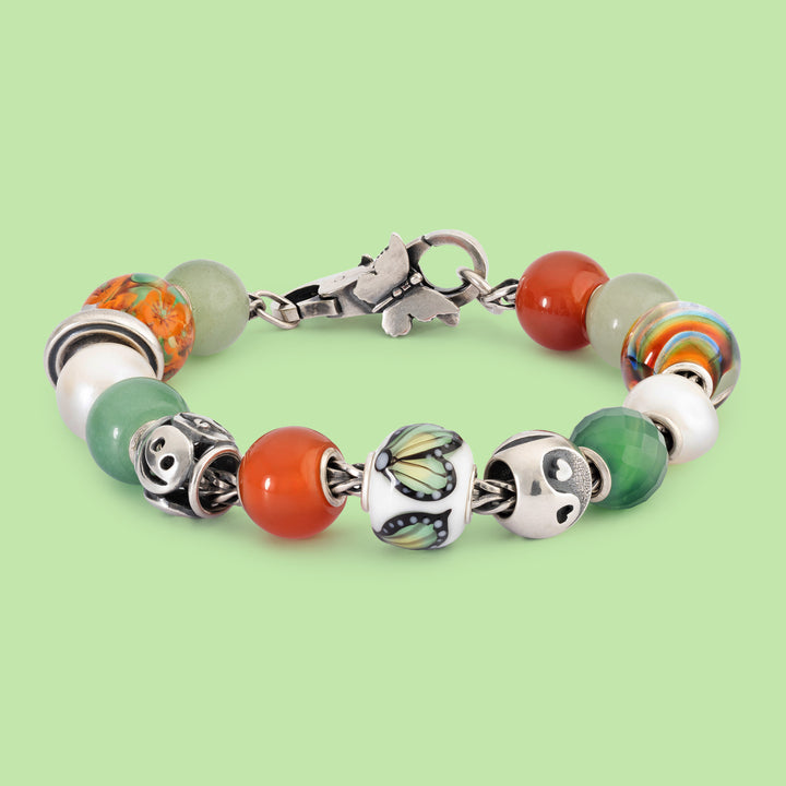 Bracelet with colorful beads and silver charms on a light green background