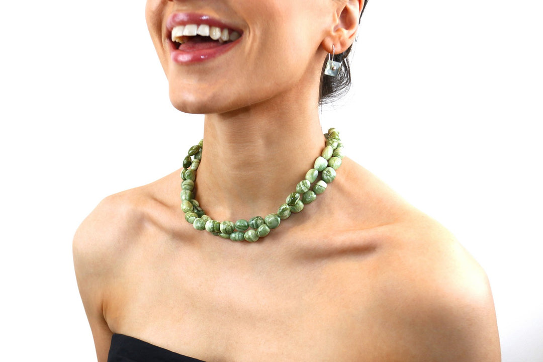 Woman wearing a green beaded necklace on a white background