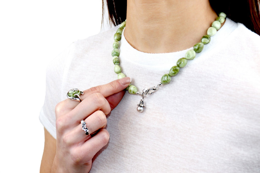 Person wearing a green beaded necklace with a white shirt