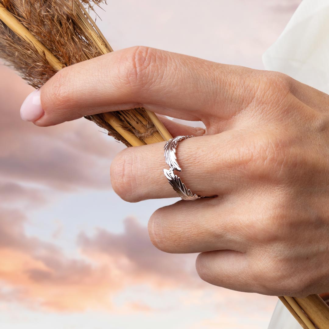 Hand wearing a silver ring holding a broom with a blurred background