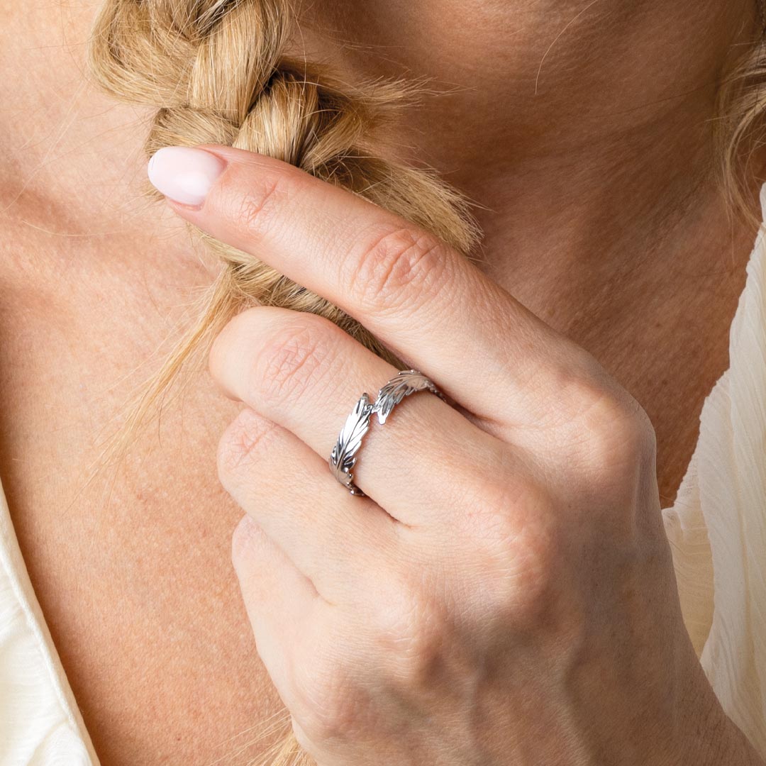 Close-up of a hand braiding hair with a silver ring on a blurred background