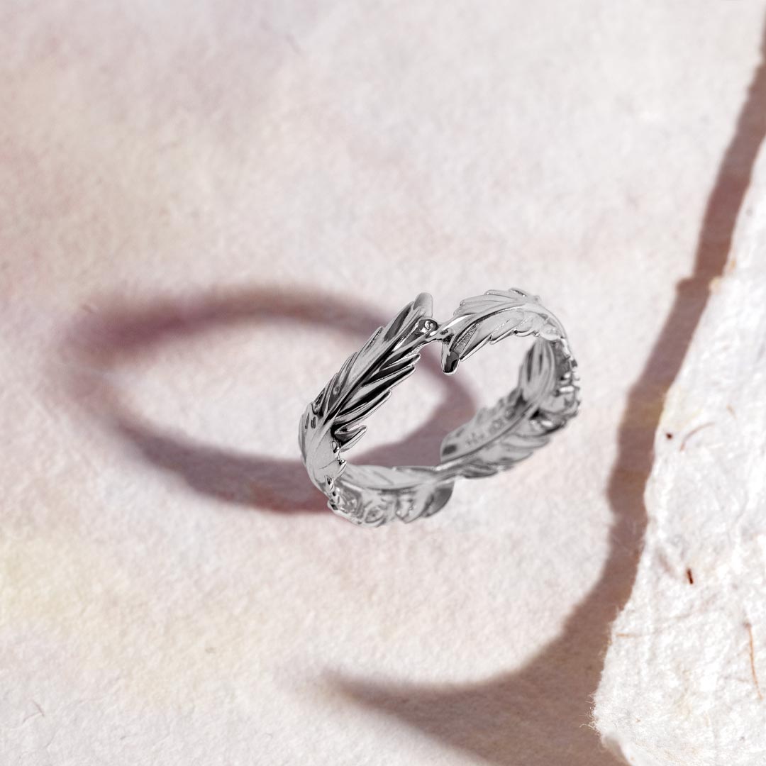 Silver ring with leaf design on a light pink background