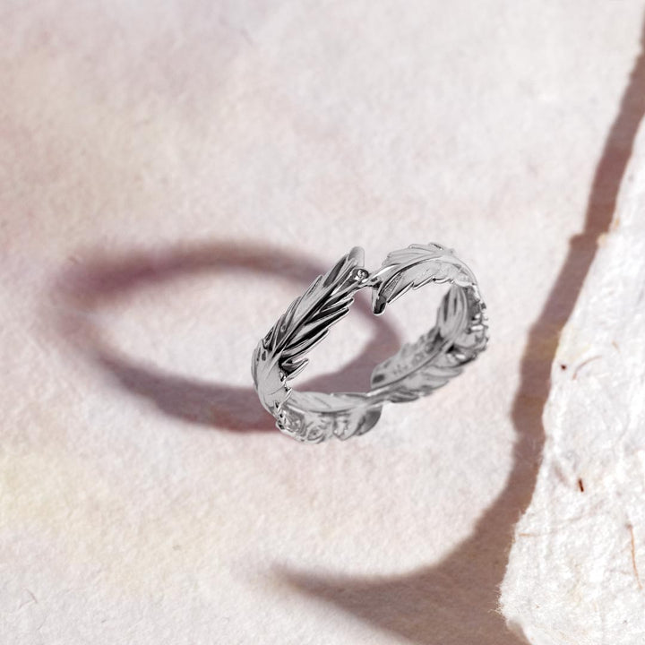 Silver ring with leaf design on a light pink background