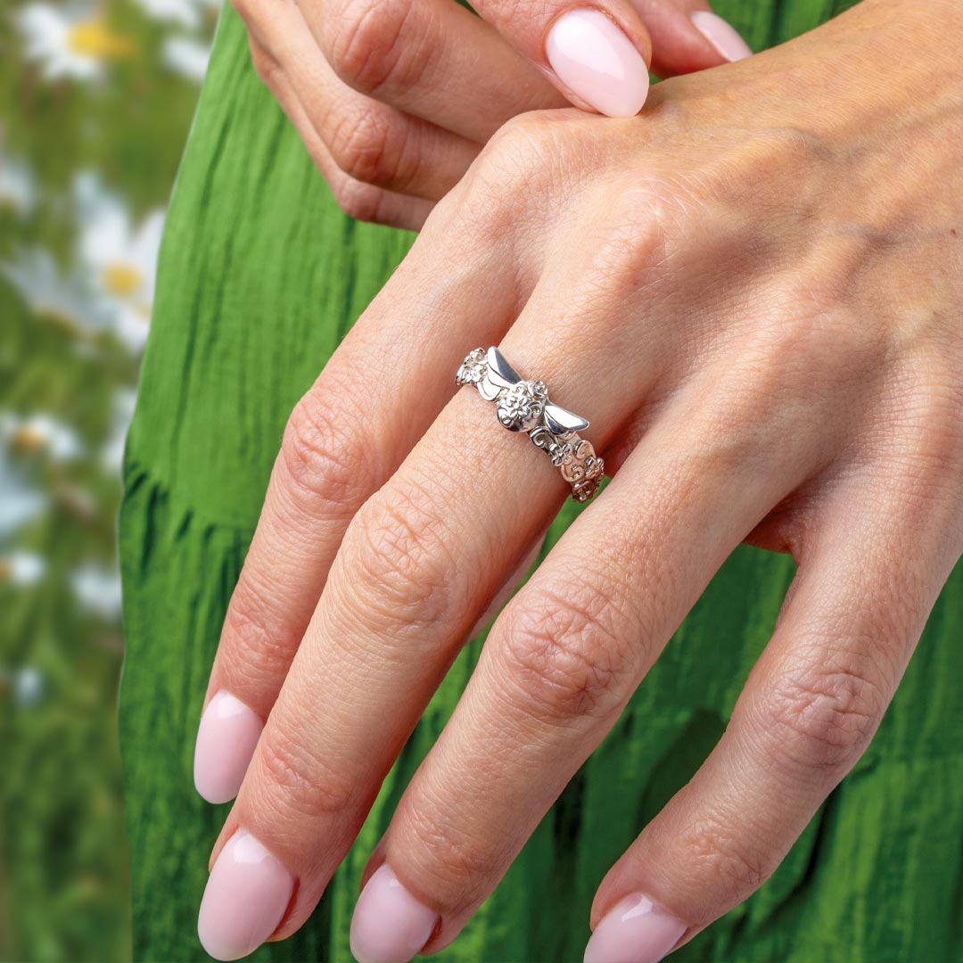 Close-up of a hand wearing a silver ring with a green leafy background