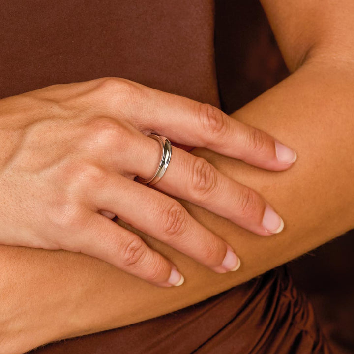 Close-up of a hand with a silver ring on a brown background
