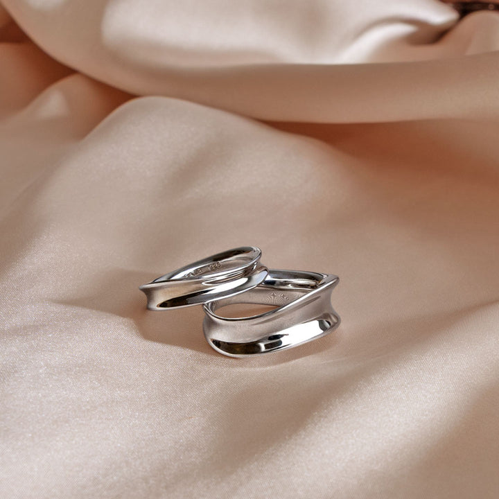 Two silver rings on a soft beige fabric background