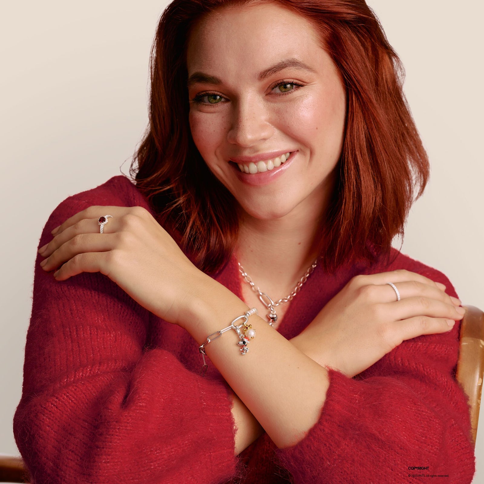 Woman wearing jewelry with a red sweater against a neutral background