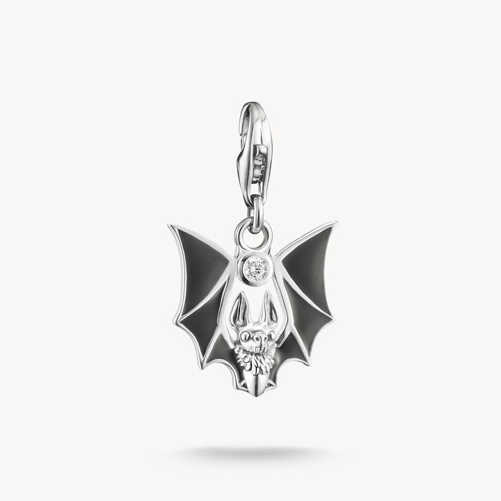 Silver pendant with black bat design on a white background