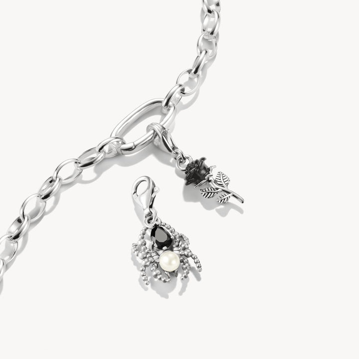 Silver bracelet with two charms on a white background
