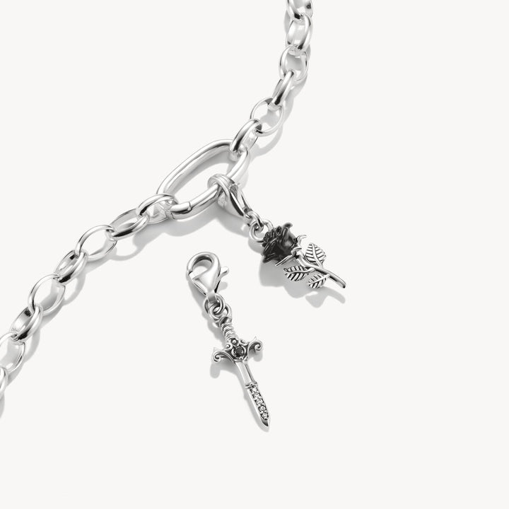 Silver chain bracelet with two charms on a white background