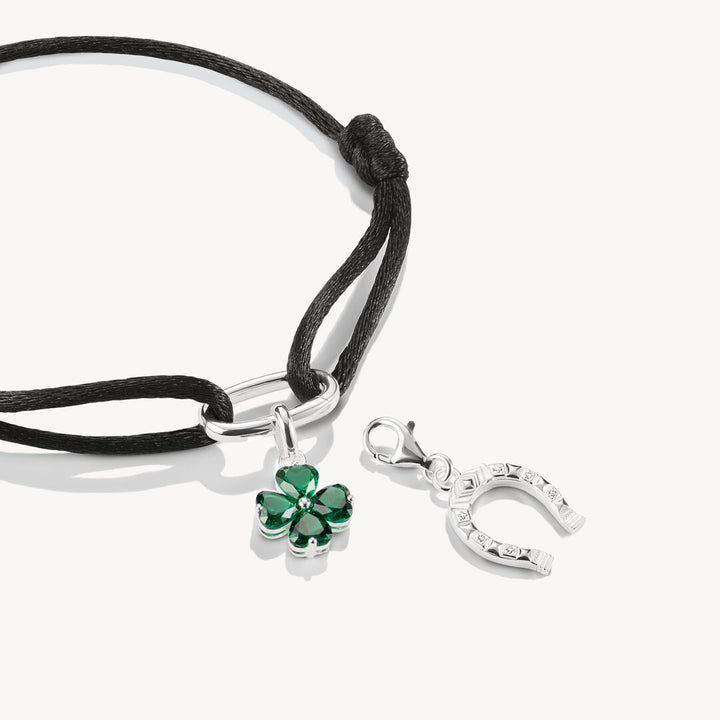 Bracelet with green clover charm and silver horseshoe charm on a white background