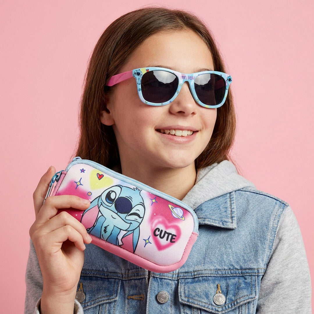 Girl wearing colorful sunglasses holding a pink pouch with cartoon character on a pink background
