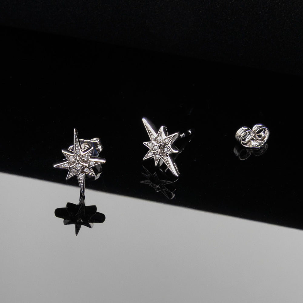 Star-shaped silver earrings on a black and gray gradient background