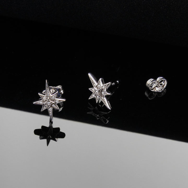 Star-shaped silver earrings on a black and gray gradient background