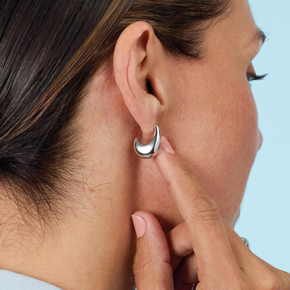 Close-up of a person wearing a silver earring with a blurred background