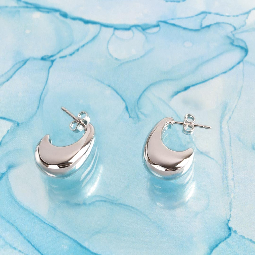 Silver moon-shaped earrings on a blue marbled background