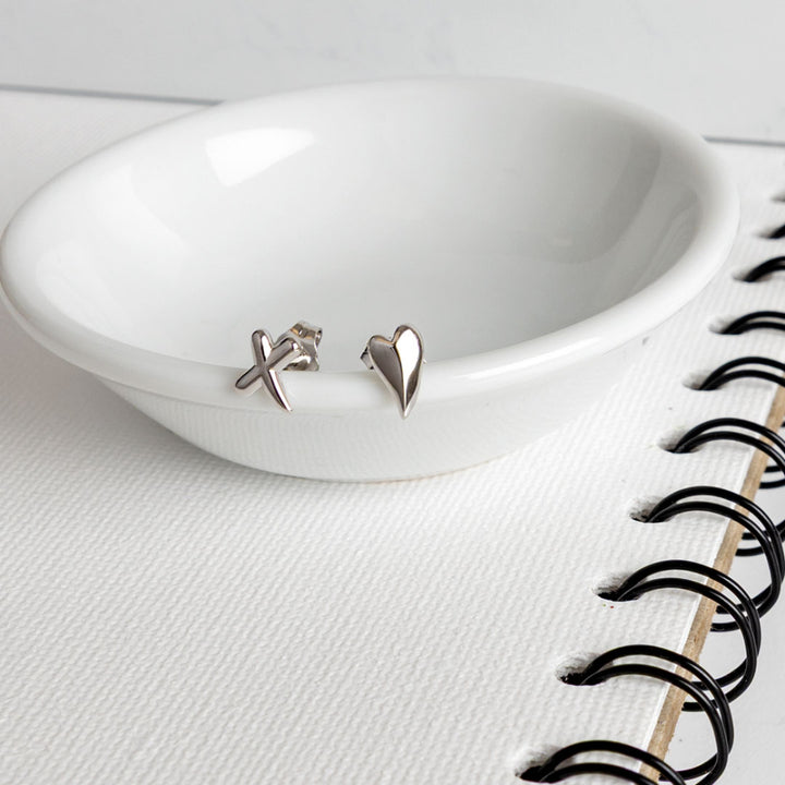Silver earrings on a white dish with a notebook in the background