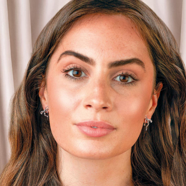 Close-up of a woman with earrings against a neutral background