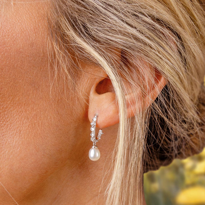 Close-up of an ear wearing a pearl earring with blurred background