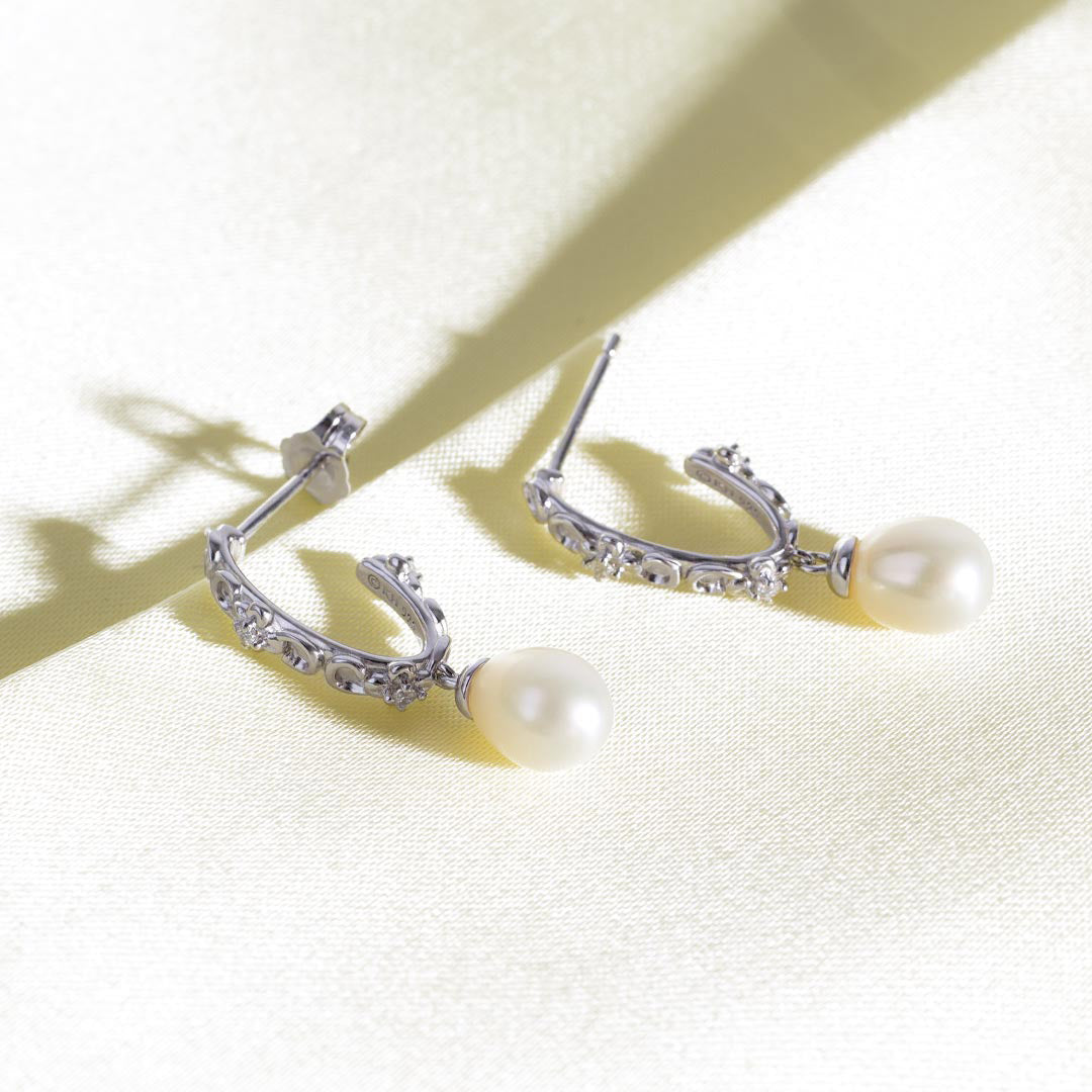 Silver earrings with pearls on a light background