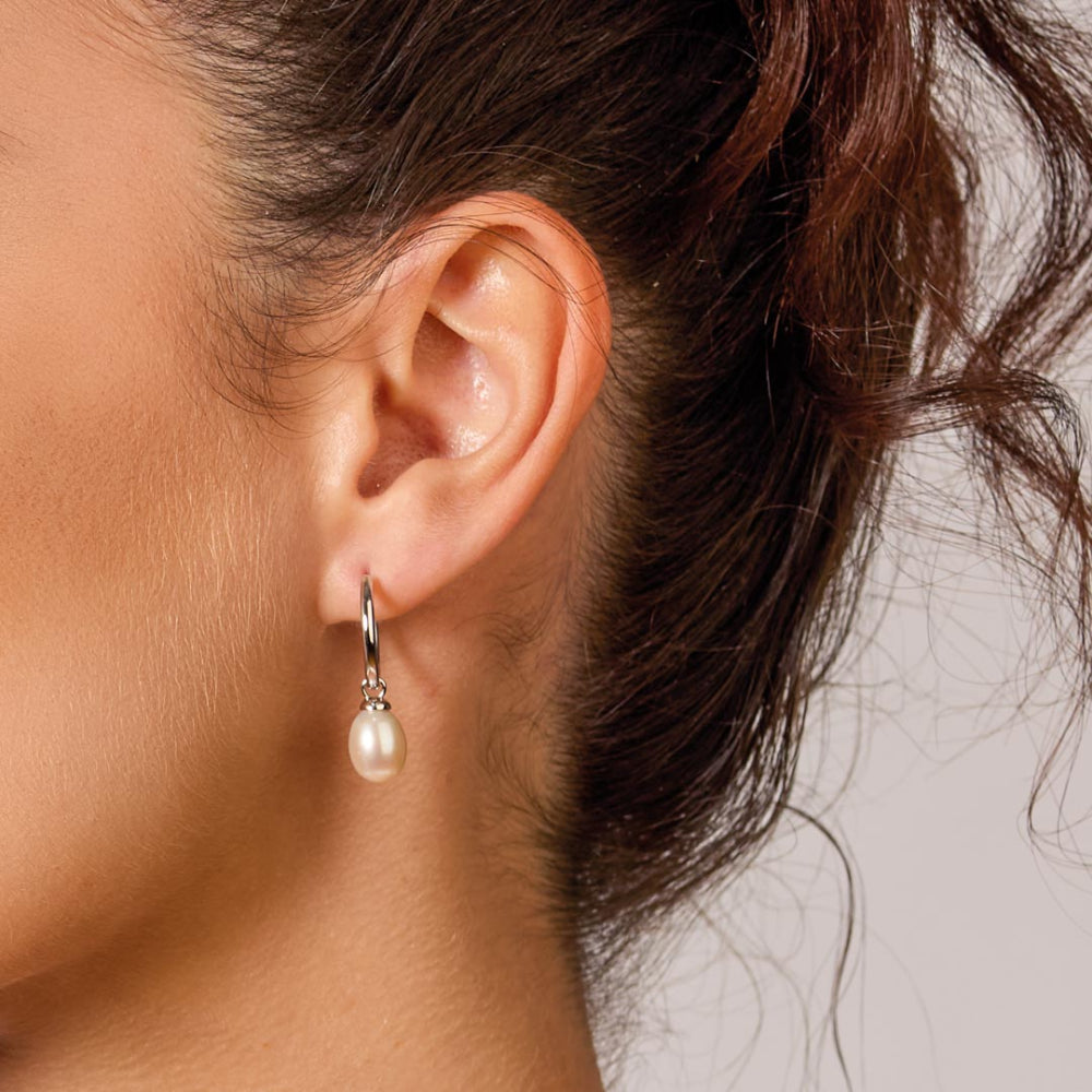 Close-up of an ear wearing a pearl earring with blurred background