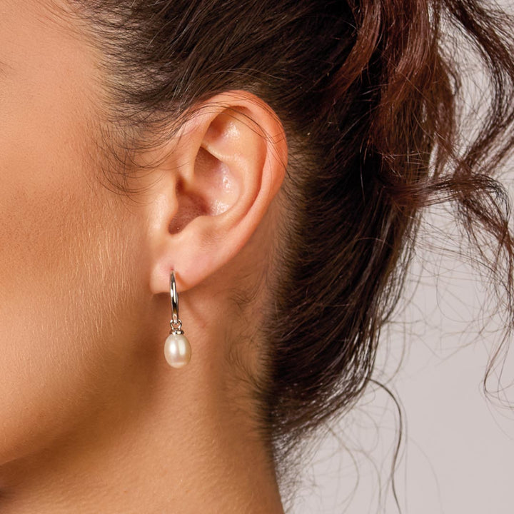 Close-up of an ear wearing a pearl earring with blurred background