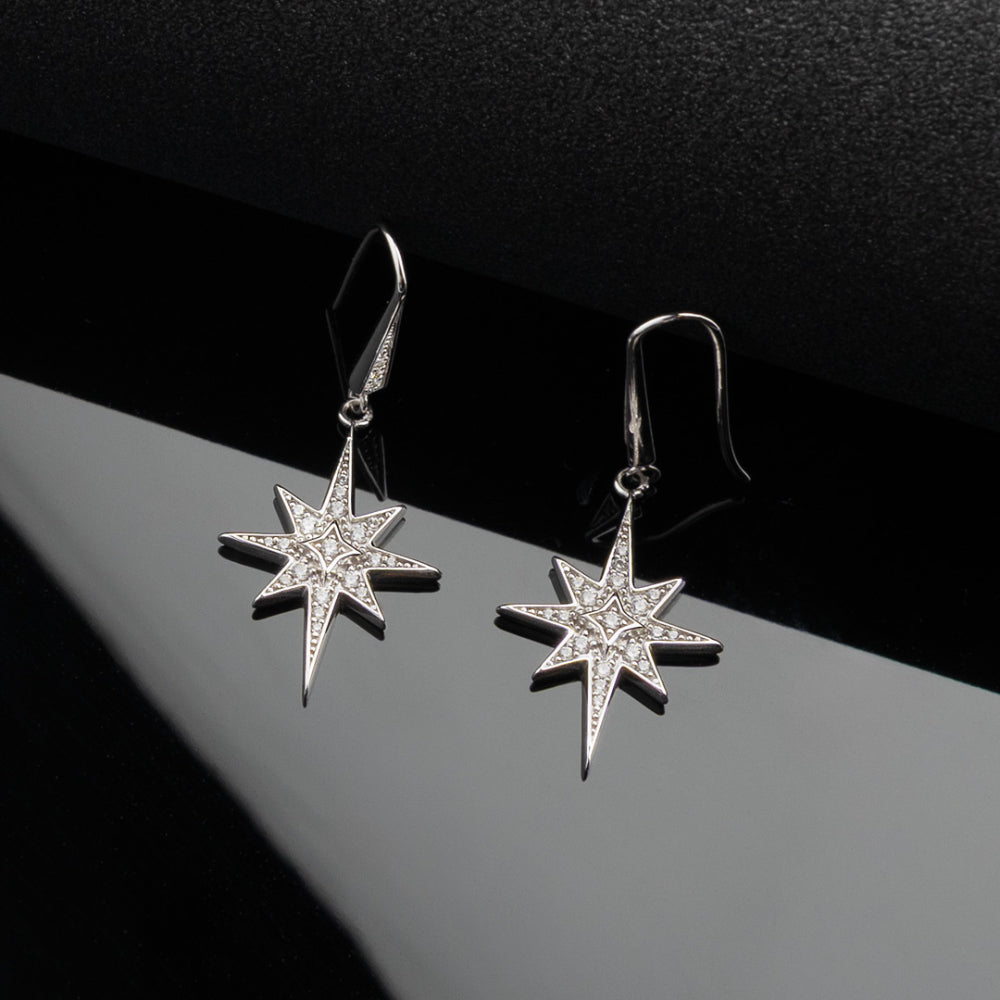 Star-shaped silver earrings on a dark background