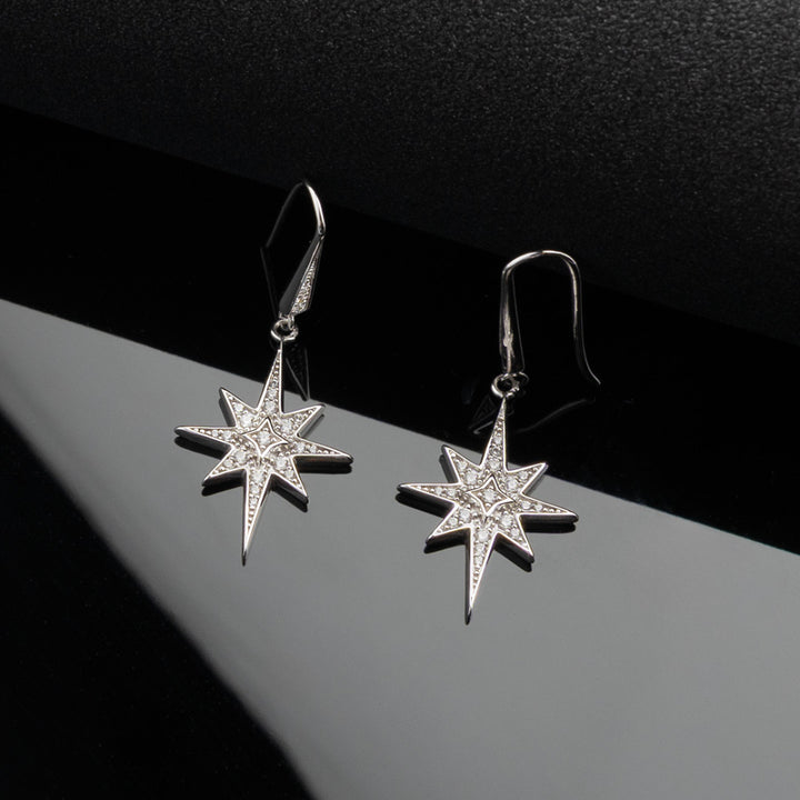 Star-shaped silver earrings on a dark background