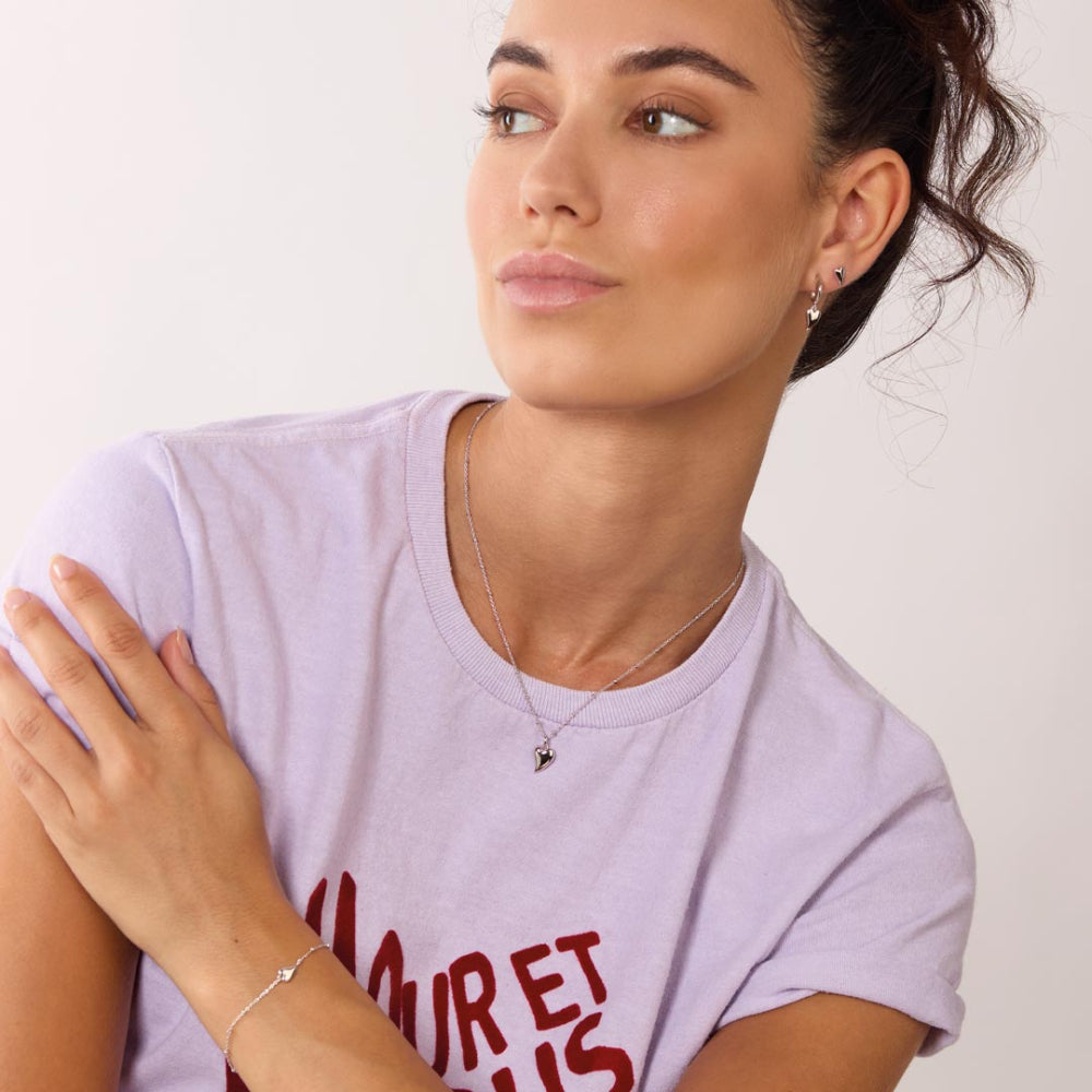 Woman wearing a light purple t-shirt with red text, looking to the side.