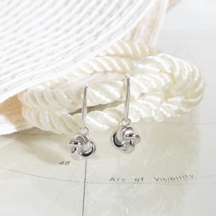 Silver earrings on a textured white surface