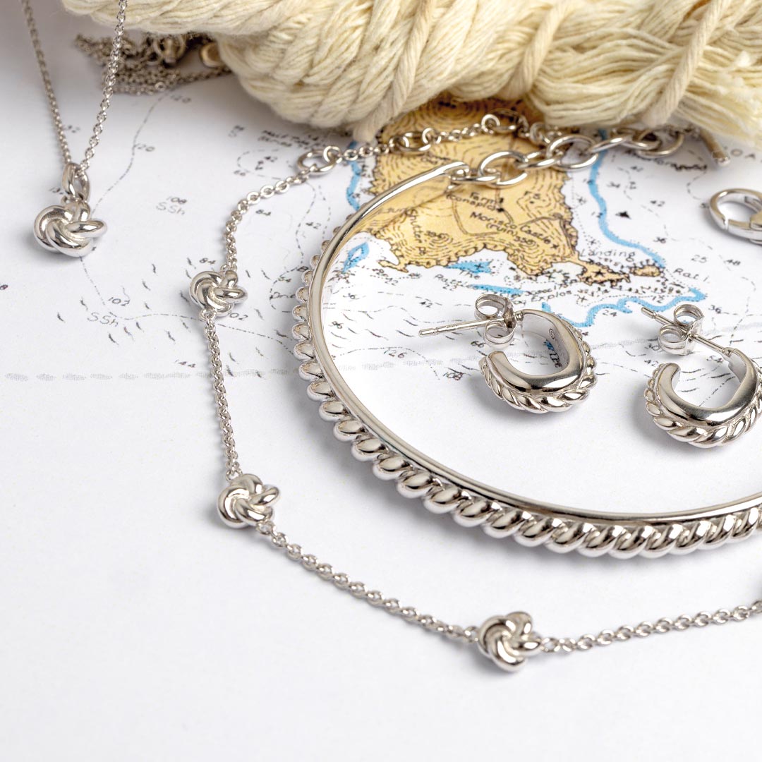 Silver jewelry set including necklace, bracelet, and earrings on a map background