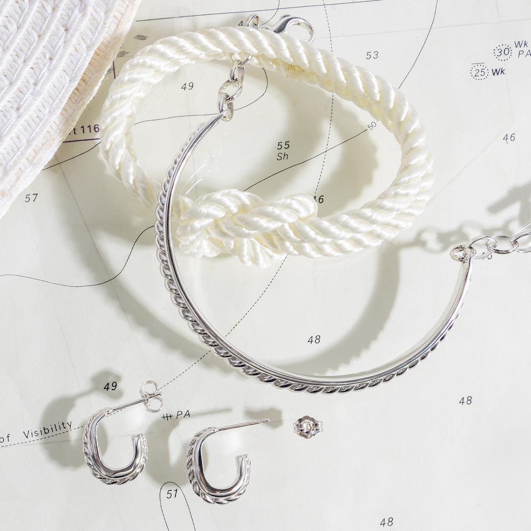 Silver hoop earrings on a white surface with measurement markings