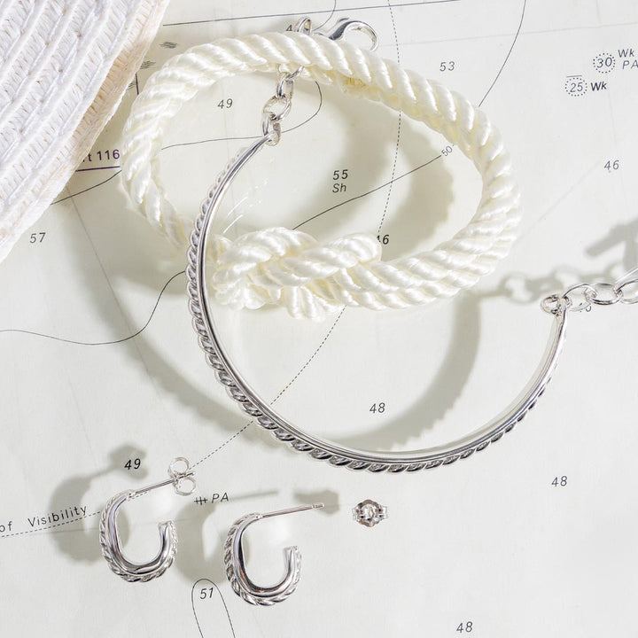 Silver hoop earrings on a white surface with measurement markings