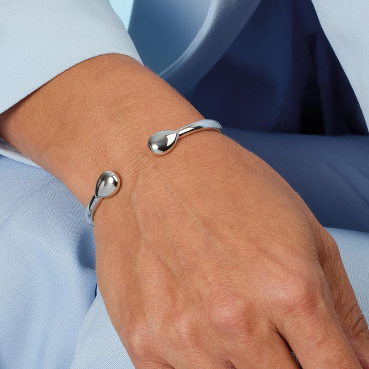 Silver bracelet on a wrist with a light blue shirt background