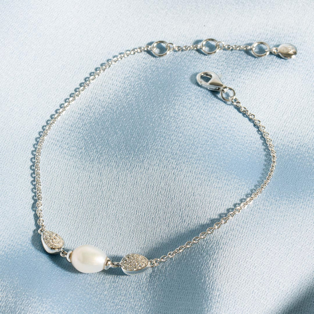 Silver bracelet with pearls on a light blue fabric background