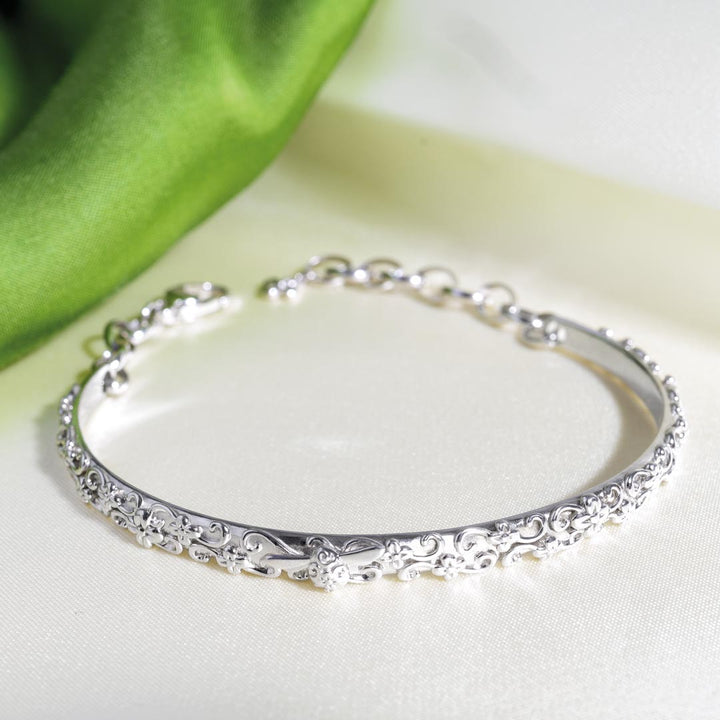 Silver bracelet with intricate designs on a white surface