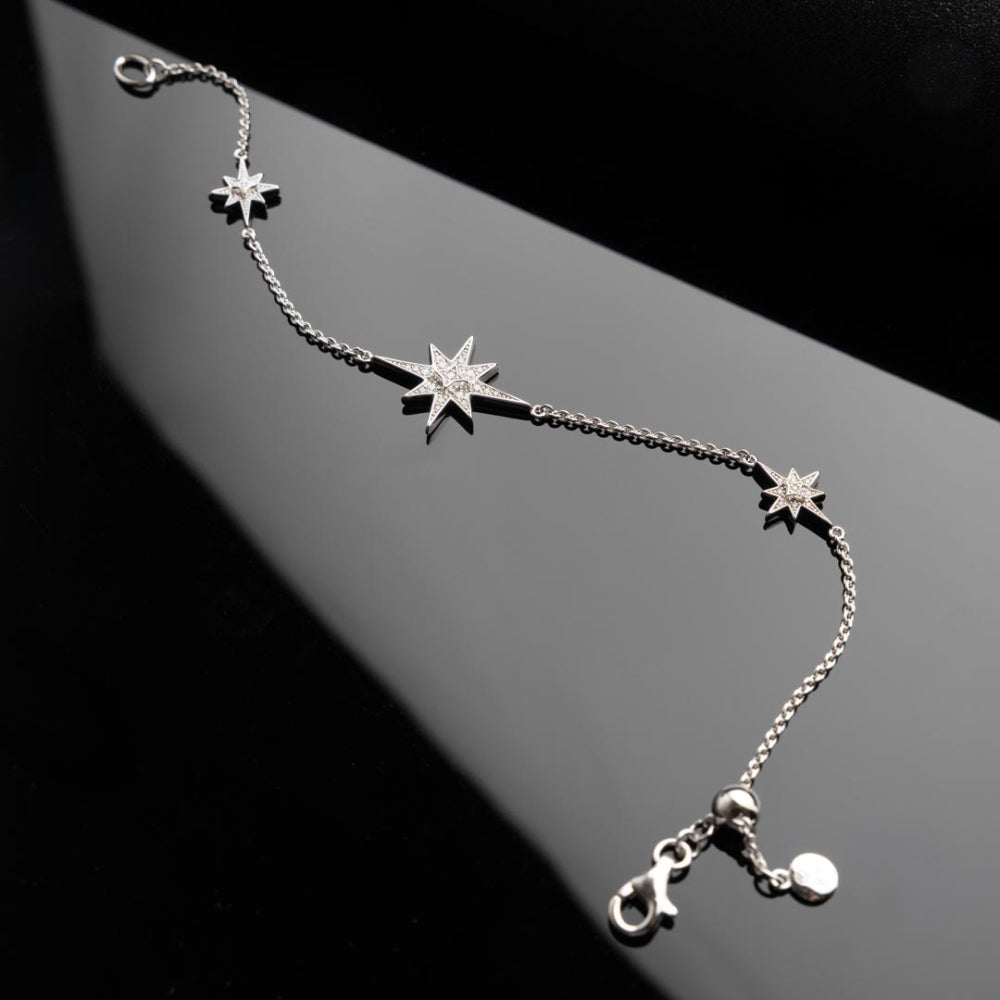 Silver bracelet with star-shaped charms on a dark background