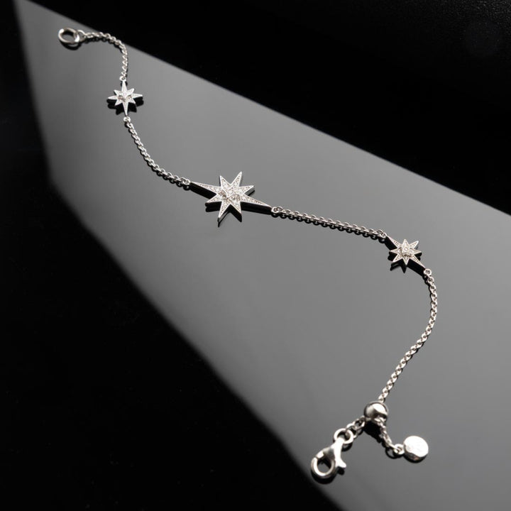 Silver bracelet with star-shaped charms on a dark background