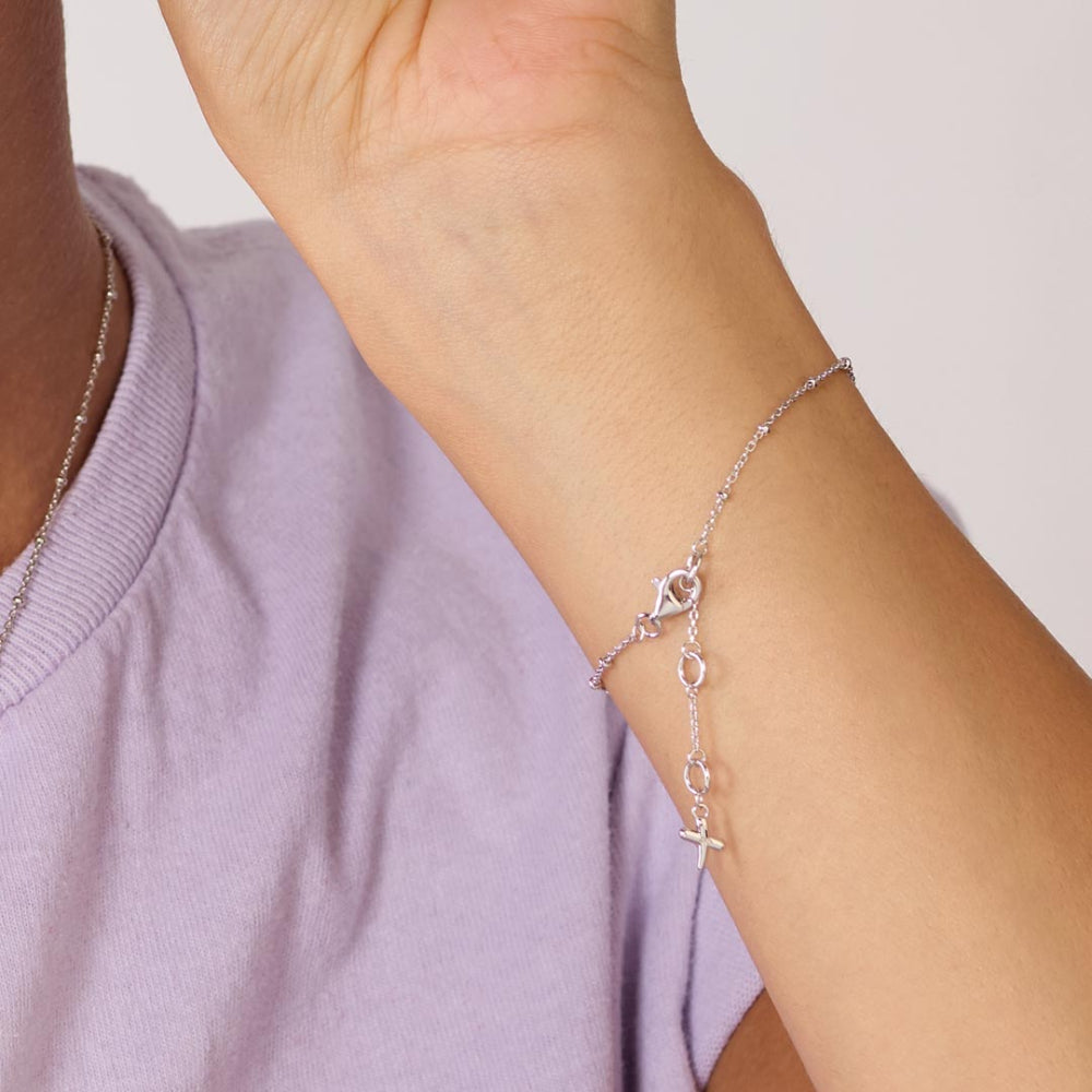 Silver bracelet on a wrist with a plain background