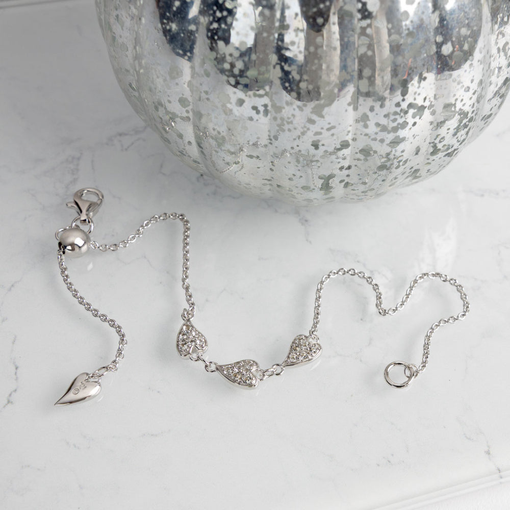Silver bracelet with heart-shaped charms on a marble surface