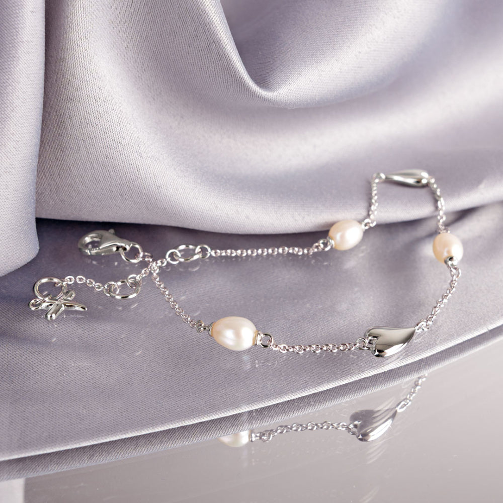 Silver bracelet with pearls on a silver fabric background