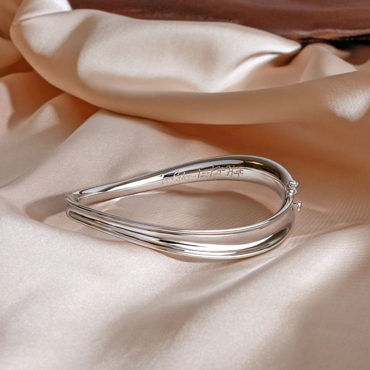 Silver bracelet on a soft beige fabric background