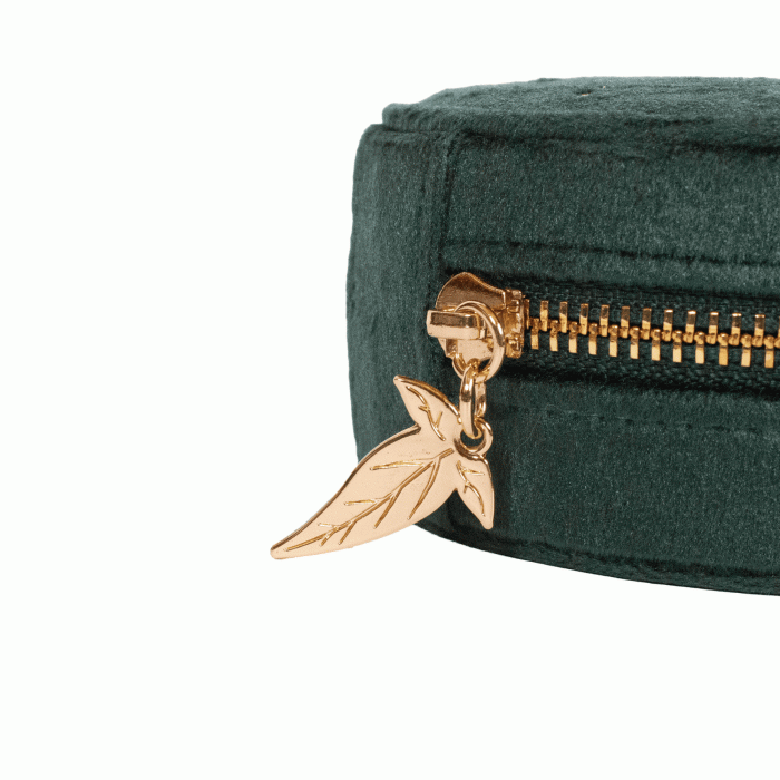 Close-up of a dark green velvet zippered pouch with a gold zipper and a dangling gold leaf charm, set against a plain white background.