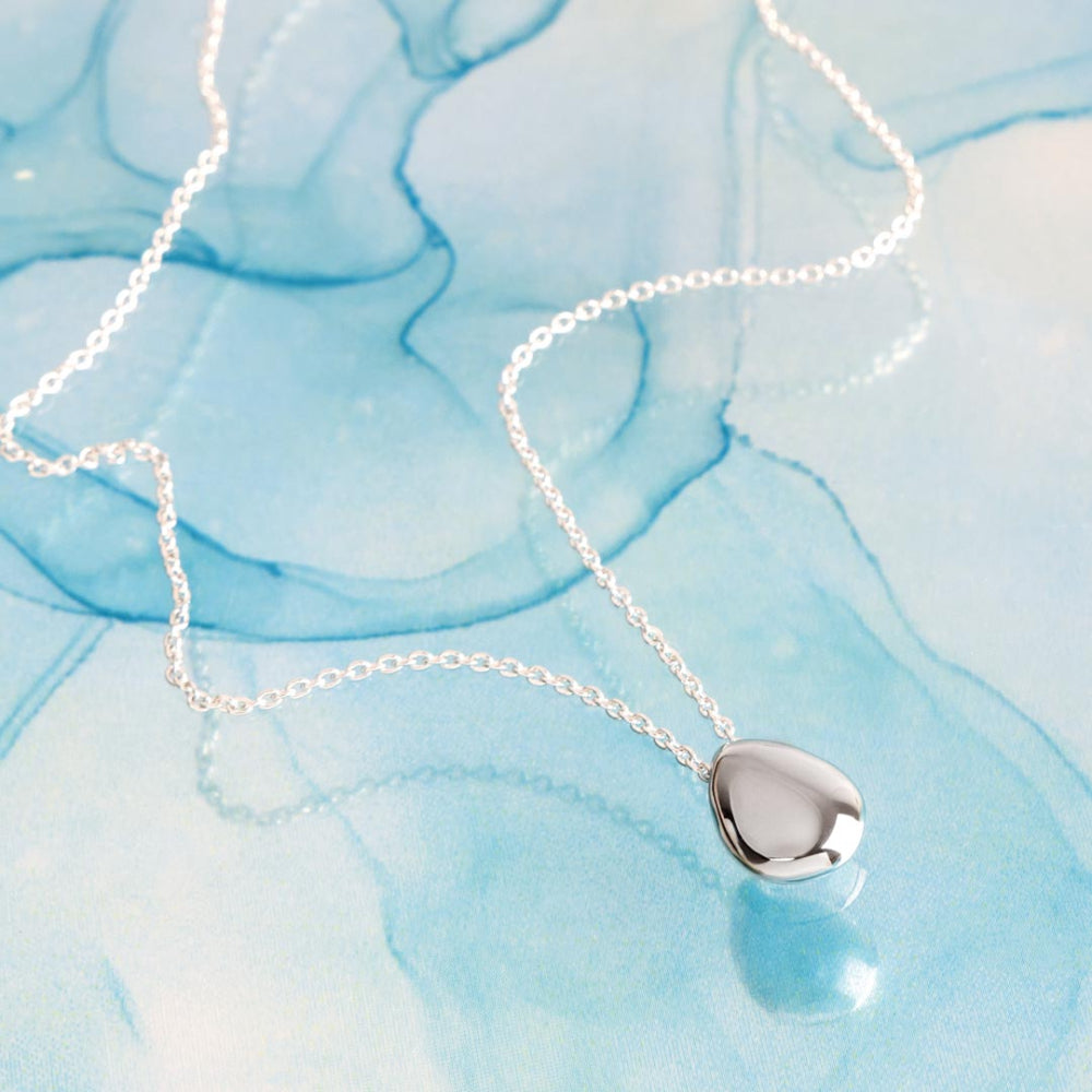 Silver heart-shaped pendant necklace on a blue marbled background